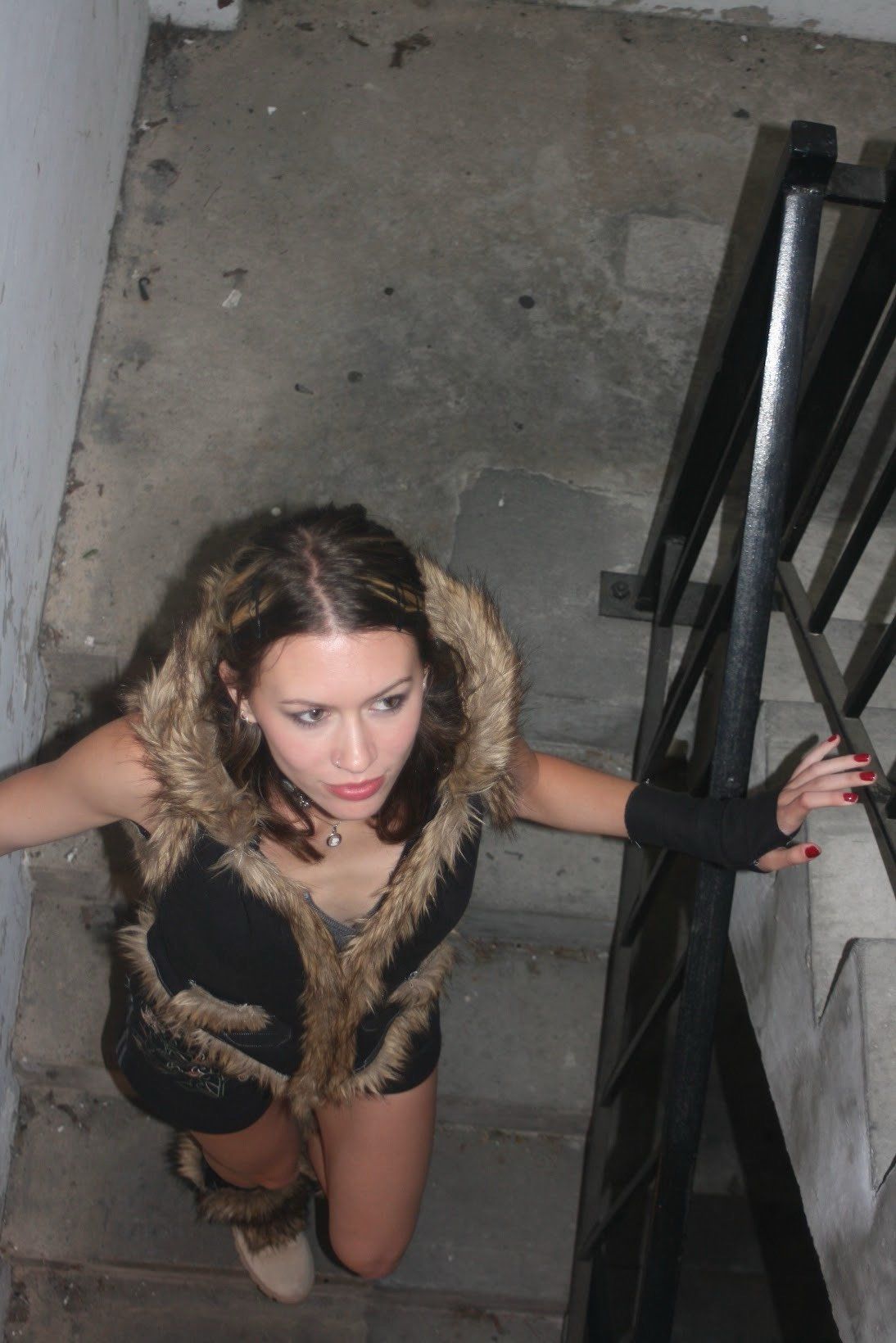 The model crouched on a concrete stairwell in the fur-trimmed hooded vest and shorts, one gloved hand on the railing.