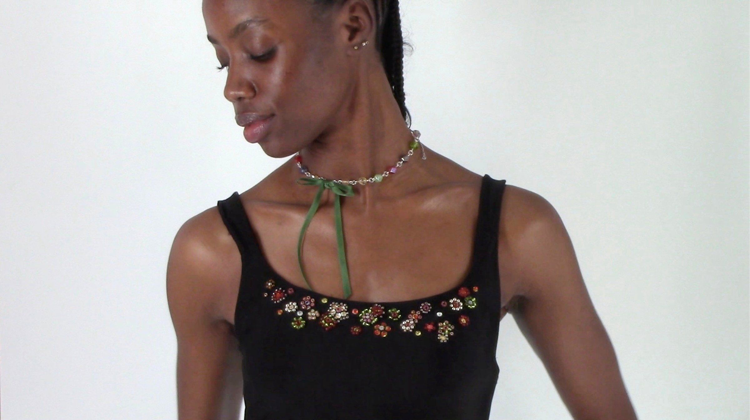 Close-up of the dress neckline with clusters of glass-bead flowers and a beaded choker tied with green ribbon.