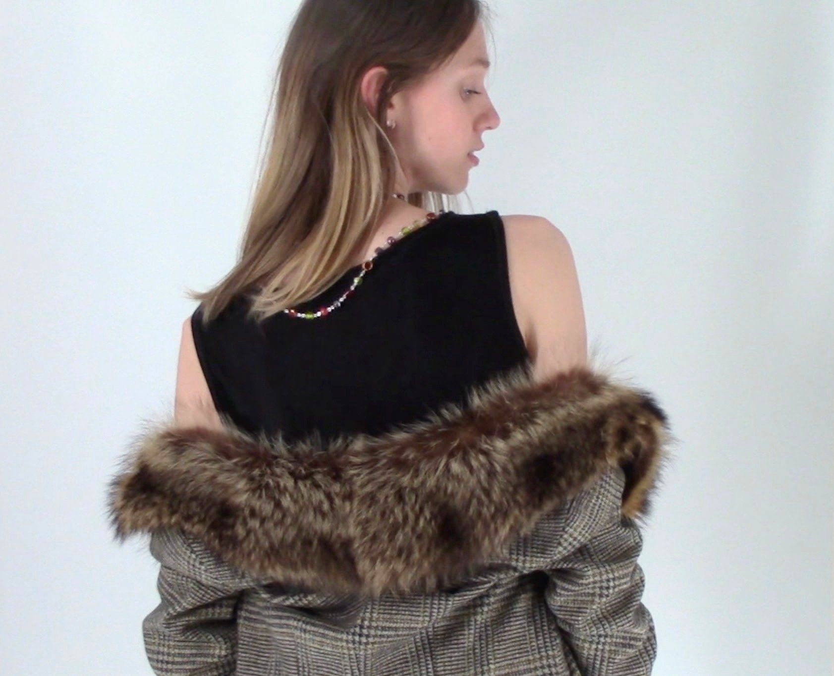 Close-up from behind of the fur collar falling off the shoulders and a beaded strand along the neckline of the black knit top.
