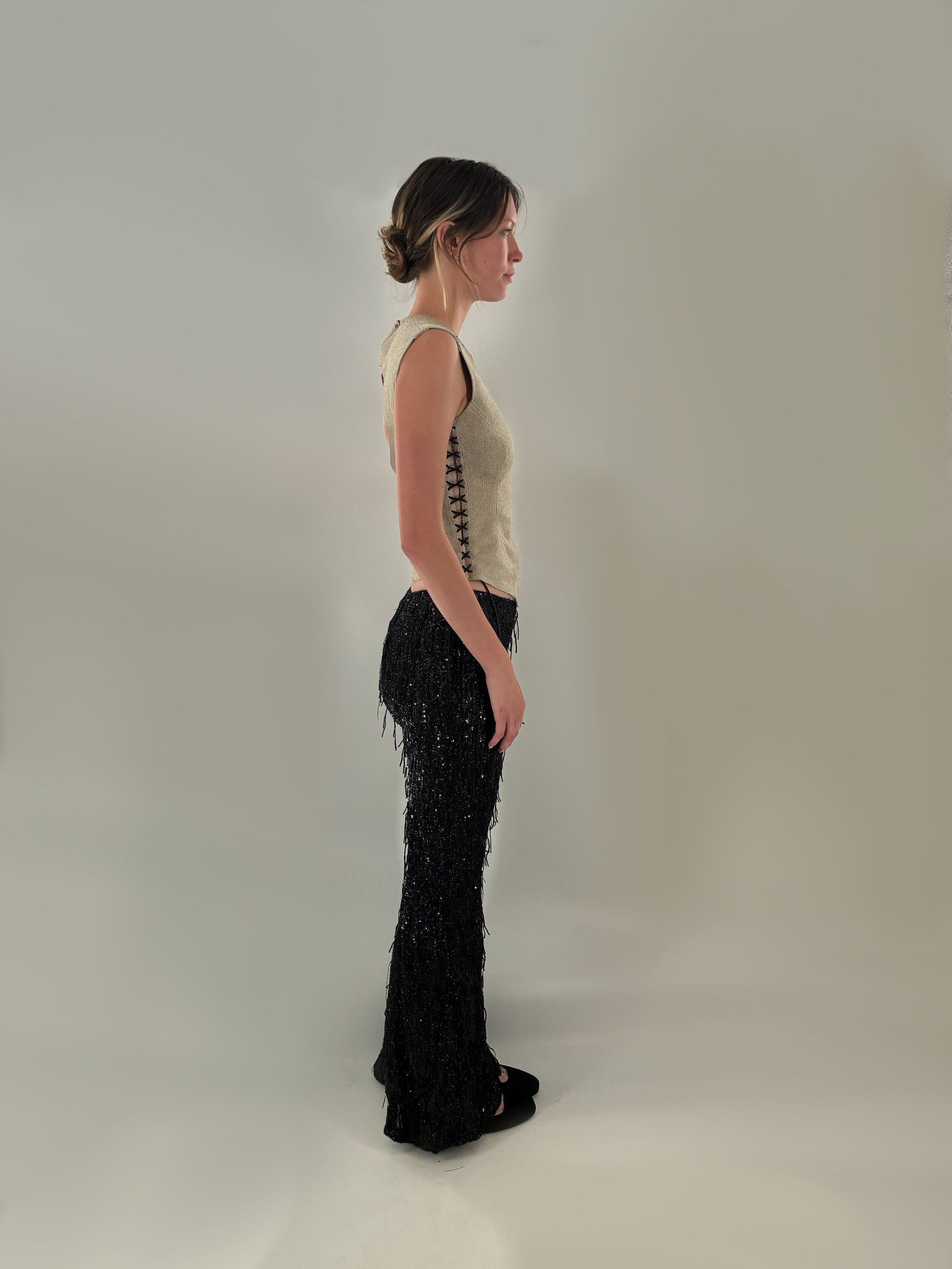 Side view of Look 6 showing the laced side seam of the suede top and the fitted, flared fringe pants.