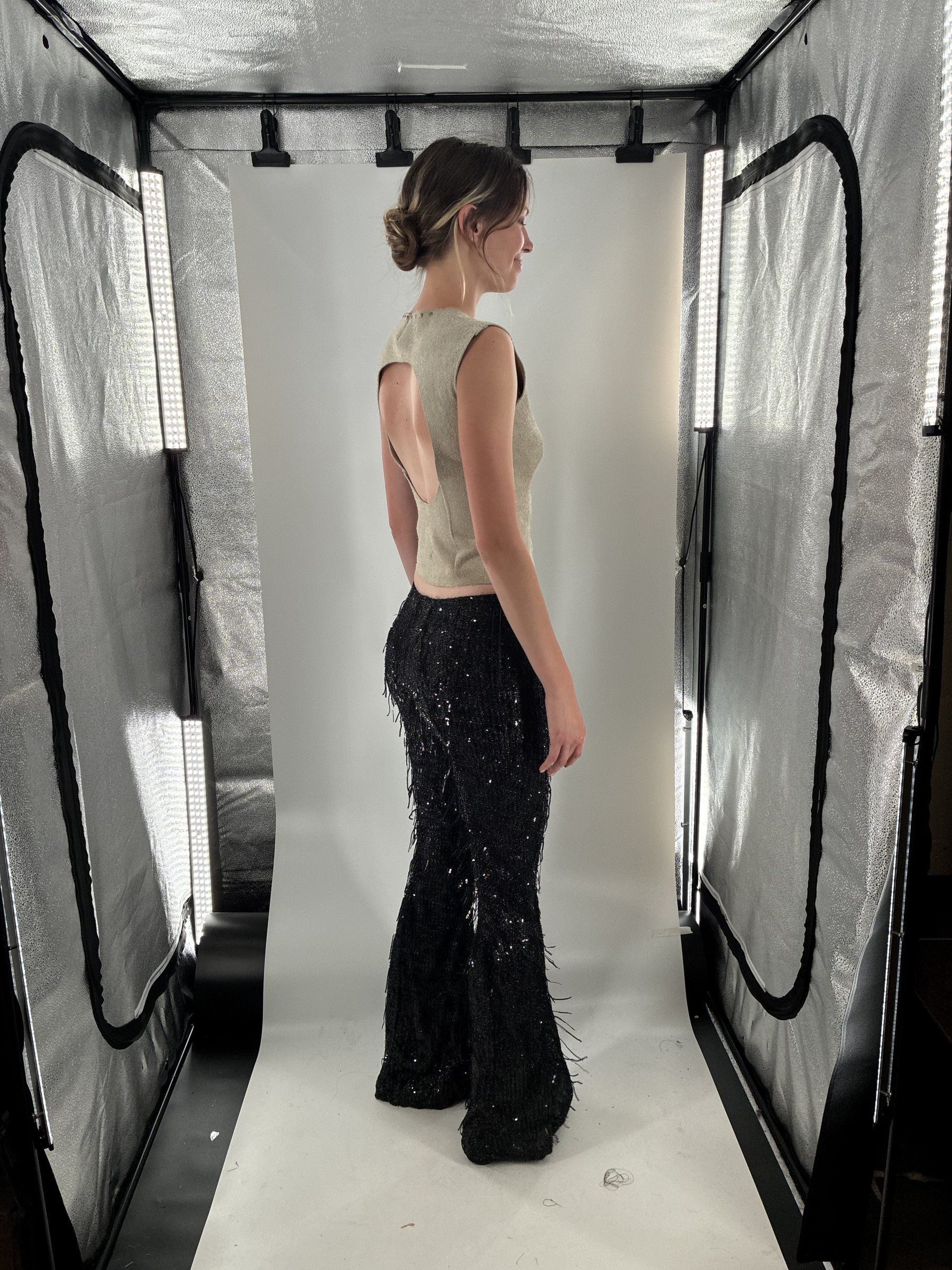 Side view of Look 6 in a lit photo tent, showing the side lace-up and the flare of the fringe pants.